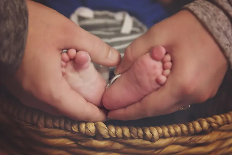 Mother holding terminal prenatal baby feet